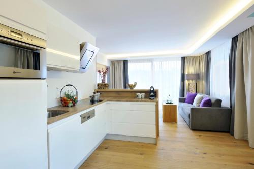 a kitchen with white cabinets and a living room at Sunnsait - Appartements für Genießer in Maria Alm am Steinernen Meer