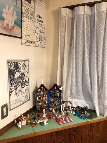 a shelf with figurines on it next to a window at Pension Moomin Papa in Myoko