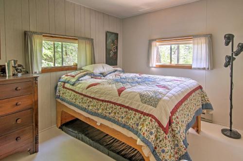 um quarto com uma cama, uma cómoda e 2 janelas em Rustic De Tour Village Cabin with Deck on Lake Huron! em De Tour Village