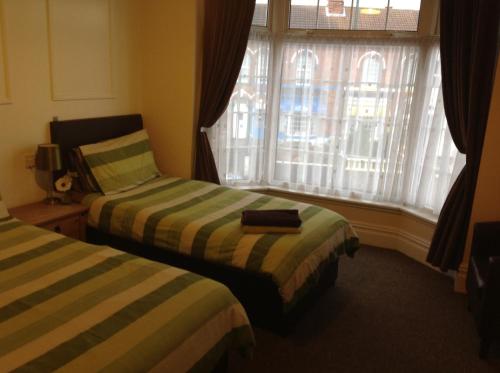 a hotel room with two beds and a window at Claydens in Cleethorpes