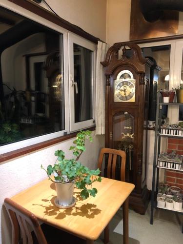 a table and a grandfather clock in a room at Pension Moomin Papa in Myoko
