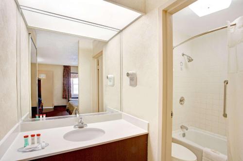 a bathroom with a sink and a shower and a mirror at Ramada by Wyndham West Memphis in West Memphis