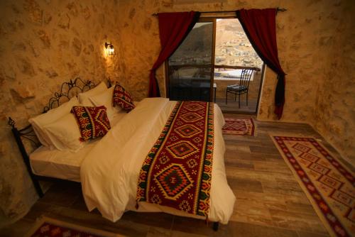 a bedroom with a large bed and a large window at Infinity Lodge in Wadi Musa