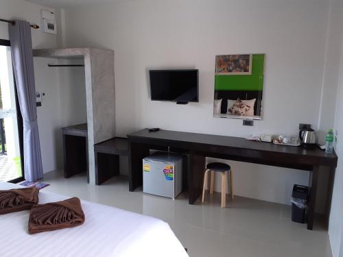 1 dormitorio con escritorio y TV. en Lanta Daisy Residence, en Ko Lanta