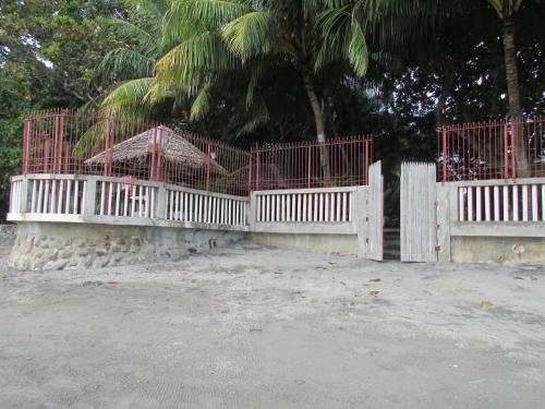 a white fence with red gates in front of a tree at Felipa Beach and Guesthouse - Gumamela in Dumaguete