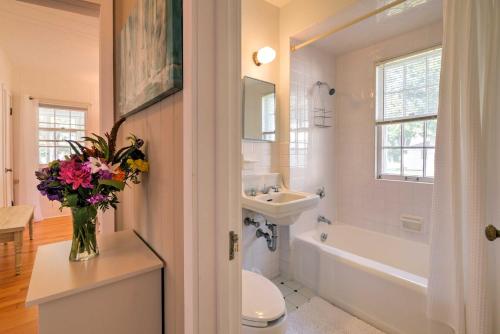 a bathroom with a toilet and a sink and a vase of flowers at Boutique Home in Door County with Eagle Harbor Views! in Ephraim