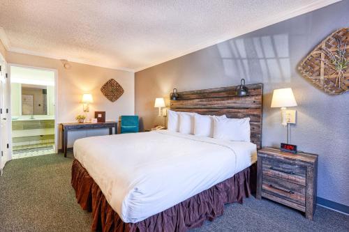 um quarto de hotel com uma cama grande e uma secretária em San Mateo Inn em Albuquerque