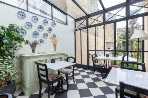 a conservatory with tables and chairs and blue plates on the wall at Villa Victor Louis - Bordeaux Centre in Bordeaux
