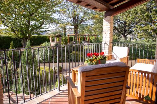 a porch with a fence and a bench and flowers at Ca' le cerque, villa surrounded by the Marche nature in Fossombrone