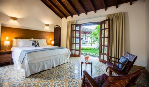 ein Schlafzimmer mit einem Bett und zwei Stühlen in einem Zimmer in der Unterkunft Hotel Boutique Adela in Granada