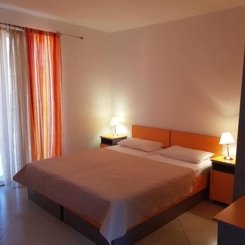 a bedroom with a bed with two lamps on two tables at Apartments Galija in Petrovac na Moru