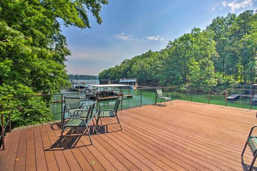 a deck with chairs and a boat on the water at Spacious Georgia Getaway with Dock on Lake Lanier! in Gainesville
