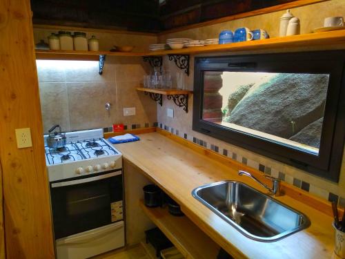 a small kitchen with a sink and a stove at Cabañas Tá Péfka in La Cumbrecita