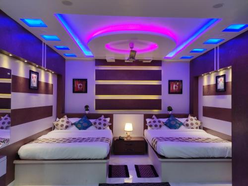 two beds in a room with purple lighting at HOTEL CENTRAL SQUARE "A Couple Friendly Hotel" in Muzaffarpur