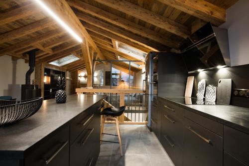 Il comprend une cuisine dotée de plafonds en bois et d'un comptoir noir. dans l'établissement Le Chalet Nativ, à Morzine