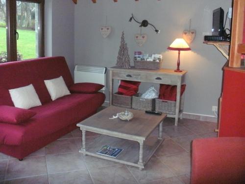ein Wohnzimmer mit einem roten Sofa und einem Tisch in der Unterkunft Gite du vieux pommier in Herbeumont