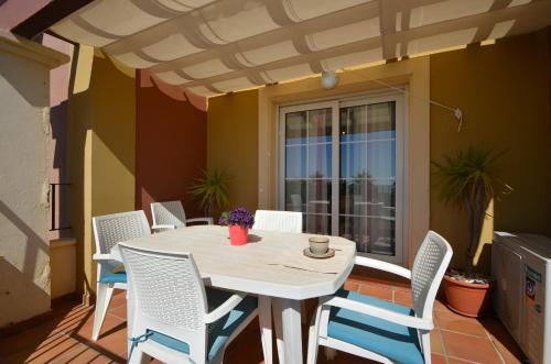 une table et des chaises blanches sur une terrasse avec une fenêtre dans l'établissement Apartamentos Solmares, à Isla Canela