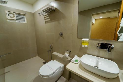 a bathroom with a sink and a toilet and a mirror at Hotel Pleasant Lake in Ahmedabad