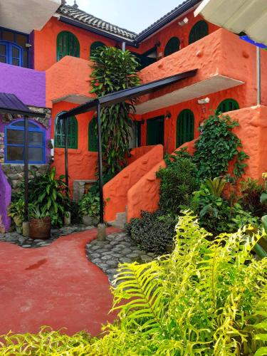 an orange house with a red driveway in front of it at CasKaffeSu Hotel and Restaurant Mindo in Mindo