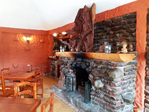 a stone fireplace in a restaurant with a table and chairs at CasKaffeSu Hotel and Restaurant Mindo in Mindo