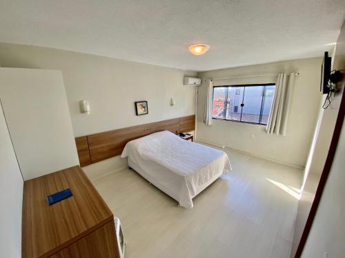 a bedroom with a white bed and a window at Scaini Palace Hotel in Arroio do Silva