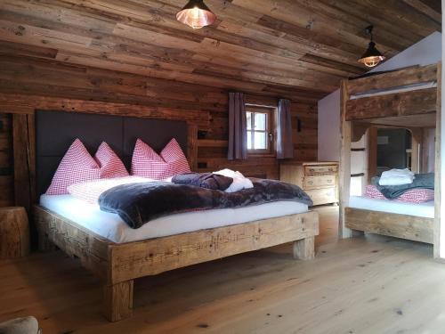 um quarto com uma cama grande num chalé de madeira em Sinnlehen Alm em Saalbach-Hinterglemm
