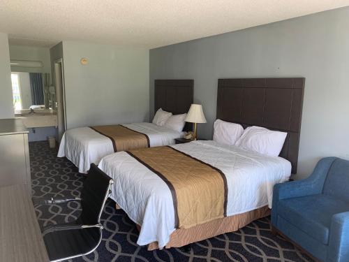 una habitación de hotel con 2 camas y una silla azul en Richland Inn - Lewisburg, en Lewisburg