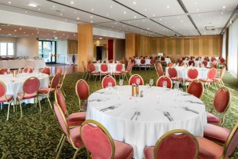 a banquet hall with white tables and red chairs at Hotel Am Sachsengang in Groß-Enzersdorf