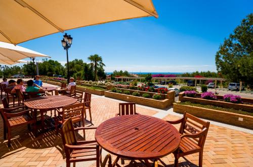 an outdoor patio with tables and chairs and an umbrella at Hotel Golf Campoamor in Dehesa de Campoamor
