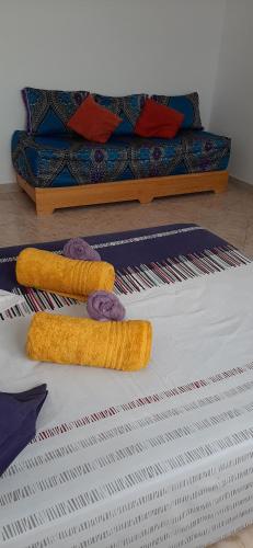 two towels on a bed with a couch in the background at Villa CLIMATISEE avec piscine privée, ras el ma in Tazagouin