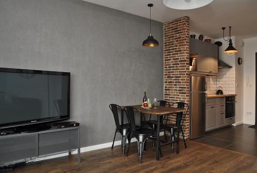 a dining room with a table with chairs and a television at Schindler’s Factory Zabłocie Deluxe Apartments WAWELOFTS in Kraków
