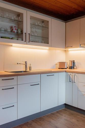 a kitchen with white cabinets and a sink at Ferienwohnung AlMa in Pflach