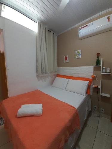 a bedroom with a large bed with an orange blanket at Suíte da Vila - Beira Mar in Abraão