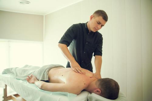 a man getting a massage from a patient in a hospital bed at Shepilska Relax Complex in Dovholuka