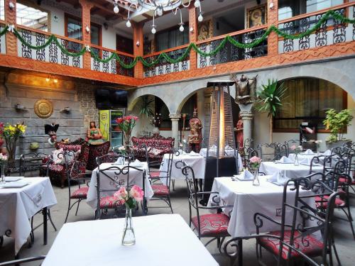 un restaurante con mesas blancas y sillas con flores. en Hotel San Francisco Plaza en Cuzco