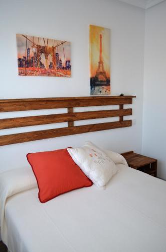 a bedroom with a white bed with a red pillow at Apartamento La Guinda in Consuegra