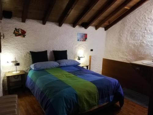 a bedroom with a large bed with blue and green sheets at Romantica casetta nel verde con vista sul lago in Belgirate