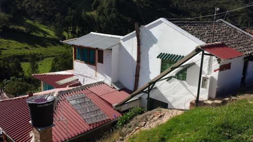 a white house with a red roof on a hill at HOSPEDAJE BELLA VISTA MONGUI in Monguí