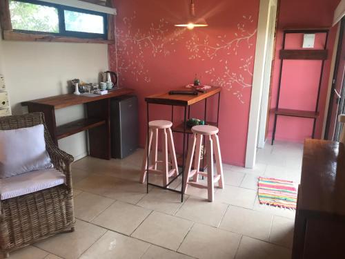 a kitchen with two stools and a pink wall at Posada de la Viuda in Punta Del Diablo
