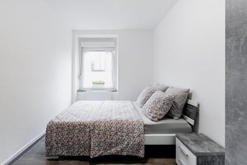 a white bedroom with a bed and a window at MyHome Basel 1A44 in Saint-Louis