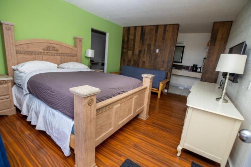 Un dormitorio con una gran cama de madera y una mesa. en Camrose Motel, en Camrose