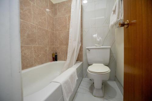 a bathroom with a toilet and a tub and a sink at Camrose Motel in Camrose