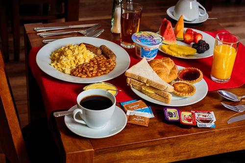 een tafel met borden ontbijtproducten en een kopje koffie bij Dockside Hotel in Londen