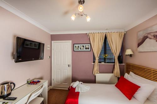 Schlafzimmer mit einem Bett, einem Schreibtisch und einem TV in der Unterkunft Dockside Hotel in London