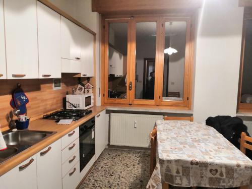 a kitchen with white cabinets and a sink and a table at da Alessandra e Fabio in Miroglio