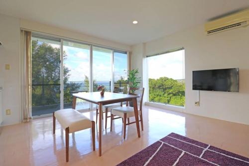 a dining room with a table and chairs and a tv at 読谷村カービラハウス ow2 in Jima