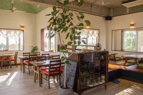 a restaurant with tables and chairs and a potted plant at 読谷村カービラハウス ow2 in Jima