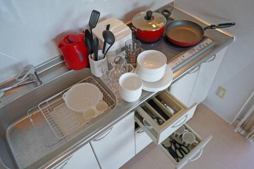 a kitchen with a sink with dishes and utensils at 読谷村カービラハウス ow3 in Jima
