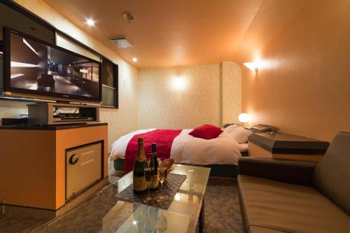 a hotel room with a bed and a couch and a television at HOTEL le ROSEY in Kitakyushu