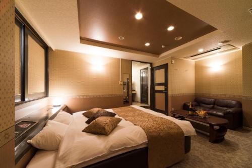 a bedroom with a large bed and a couch at HOTEL le ROSEY in Kitakyushu